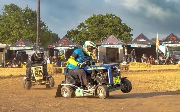 stock image Racing lawn mower drivers bounce around a corner at sunrise after dring all night in the BLMRA 500, a Le Mans style 500 mile overnight lawn mower race in a field in West Sussex, UK.