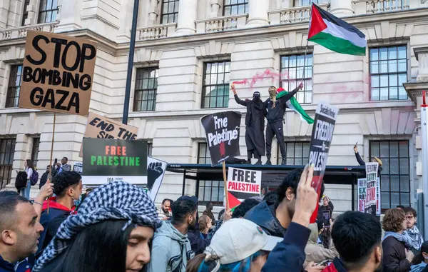 stock image London, UK. 14 Oct 2023: Pro-Palestinian protesters stand on a bus shelter holding a red flare and Palestinian flag as a protest in support of Palestine and against  Israeli attacks on Gaza passes.