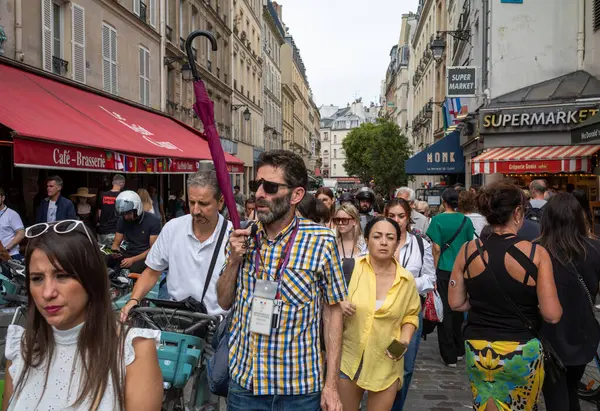 Bir tur rehberi, bir grup turisti Paris, Fransa 'daki kalabalık Latin Mahallesi' nden geçirirken bir şemsiye tutuyor..