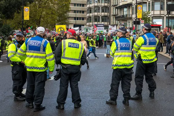 stock image London / UK - Oct 21 2023: A group of Metropolitan Police officers stand next to thousands of pro-Palestinian protesters at a demonstration against Israeli attacks on Gaza in central London, UK.