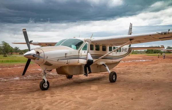 stock image A pilot climbs into the cockpit on a 12-seat Cessna light plane operated by Auric Air Services at Mtemere airstrip at Nyerere National Park (Selous Game Reserve) in Tanzania.