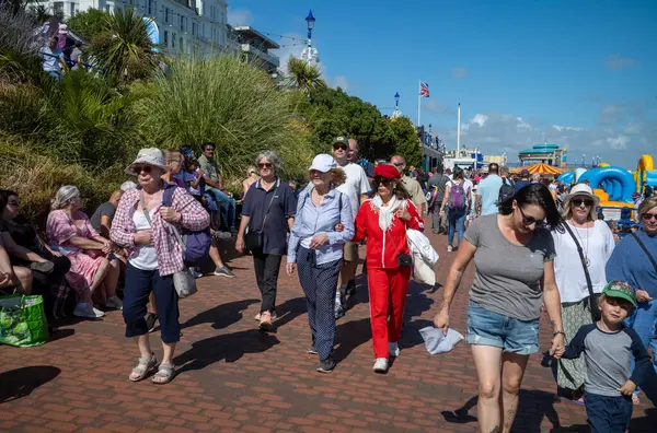 stock image Two stylish elderly women walk arm-in-arm in crowds along the promenade on Eastbourne seafront as they attend the annual Eastbourne Airbourne, an international airshow