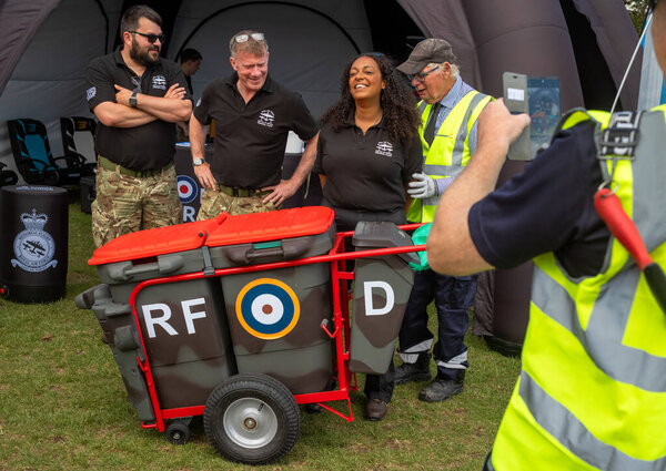 An elderly municipal bin man with his bins painted in the military camoflage colours and with a RAF roundel poses for a photo with support team members of the RAF Battle of Britain Memorial Flight at the military exhibition alongside 