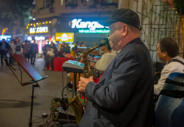 stock image A Vietnamese man plays saxophone in a band in the street at night in Hanoi, Vietnam