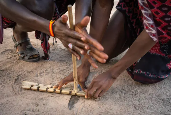 stock image Two Maasai warriors use friction by rubbing sticks together to start a fire in a village in Mikumi, Tanzania.