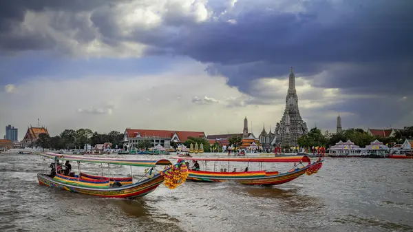 Geleneksel turist gezileri için uzun tekneler Chao Phraya Nehri 'nden geçerek Wat Arun ya da Tayland' ın Bangkok kentindeki Şafak Tapınağı 'na gider..