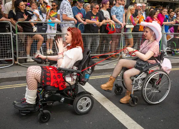 stock image London / UK - Jun 29 2024: Two lesbians in wheelchairs at the annual Pride in London parade. The celebration brings together people from LGBTQ+ communities.