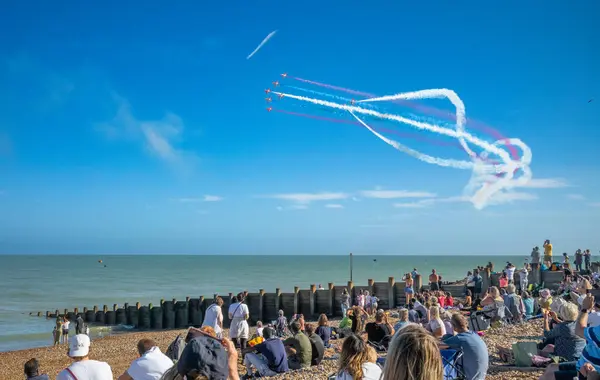 stock image People watch from Eastbourne beach as the world famous RAF display team The Red Arrows fly past the seafront at the annual Eastbourne Airbourne, an international airshow