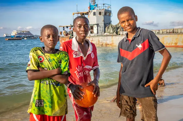 Stock image Three boys with their football next to a landing craft on the beach in Stone Town, Zanzibar, Tanzania