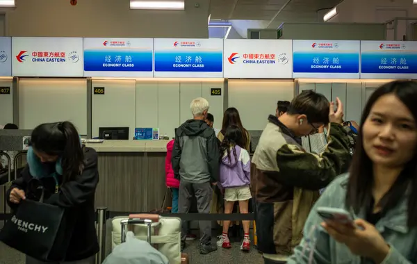 stock image Chinese passengers queue to check in for a China Eastern flight to Shanghai from London Gatwick Airport, UK.