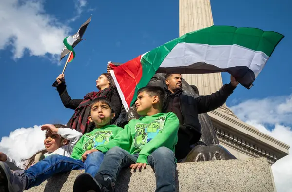 Londra, İngiltere. 14 Ekim 2023: Müslüman ebeveynler, Filistin 'i desteklemek ve İsrail' in Gazze 'ye düzenlediği saldırılara karşı Nelson' ın köşesinde üç küçük çocuğuyla bayrak sallıyor.