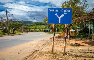 Kamboçya ve Laos sınırlarını gösteren QL40 yolundaki mavi yol işareti Vietnam 'ın Orta Highlands bölgesindeki Ngoc Hoi bölgesinde Bo Y komünü içinde.