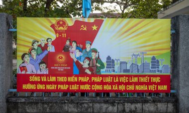 Vietnam 'ın orta dağlıklarında, Kontum' daki bir kantin okulunun kapısına iliştirilmiş, vatandaşları kanuna uymaya teşvik eden boyalı bir komünist propaganda panosu.. 