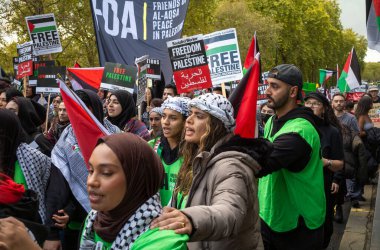 Londra / İngiltere - 21 Ekim 2023: Müslüman kadınlar, diğer Filistinli protestocularla birlikte Londra 'nın merkezinde İsrail' in Gazze 'ye düzenlediği saldırılara karşı düzenlenen büyük bir gösteride pankart ve bayraklar tutuyorlar..