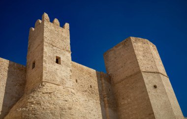 A square turret with crenellated ramparts on the outside of the 8th century Ribat of Monastir, Tunisia. clipart