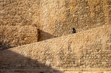 Tunus, Manastır 'da 8. yüzyıldan kalma bir İslam kalesi olan Ribat of Manastırı' nın duvarlarında akıllı telefonu, dokusu ve geometrik desenleri olan bir kadın.