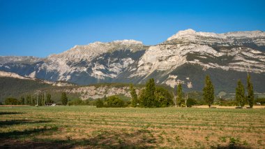 Looking west across fields from the town of Varces-Allires-et-Risset, Isere, France, towards the mountains in Parc Naturel Rgional du Vercors (Vercors Natural Regional Park) in the foothills of The Alps.  clipart