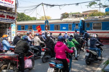 Vietnam 'da, Hanoi, Vietnam' da bir tren, insanları motosiklet ve bisikletle bir geçitten geçiyor..