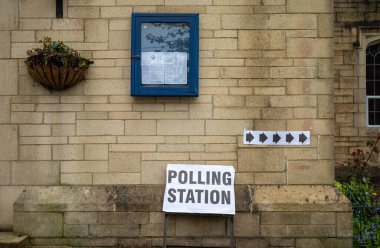 Katolik kilisesinin dışındaki işaretler, arkadaki kilise binasındaki seçim sandıklarını işaret ediyor. Billingshurst, Batı Sussex, İngiltere..