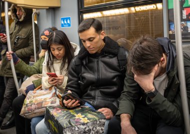 Yolcular, İtalya, Milan 'da bir metro treninde kafasını dinlendiren bir adam cep telefonlarına bakar..