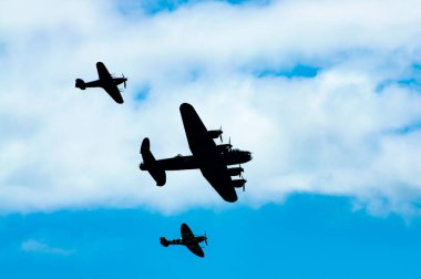 2. Dünya Savaşı 'ndan kalma Lancaster, Spitfire ve Hurricane' den oluşan Britanya Anma Savaşı, uluslararası bir hava gösterisi olan Eastbourne Airbourne 'da sahilin önünden geçerken siluette görülüyor.