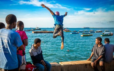 Gençler deniz duvarından atlayıp suya atlıyorlar. Stone Town, Zanzibar, Tanzanya 'da sular yükselince.