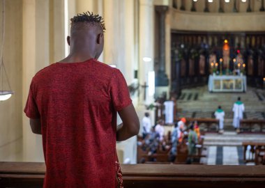 Küçük tüyleri olan ve kafası kazınmış genç bir adam, Tanzanya 'nın Zanzibar şehrindeki Anglikan İsa Kilisesi Katedrali' nde Pazar ayininde dua ediyor..