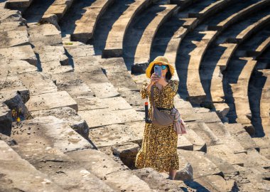 Vietnamlı bir kadın, Antalya, Türkiye 'deki büyük Roma amfitiyatrosunu ziyaret ederken cep telefonuyla fotoğraf çekiyor (Türkiye))