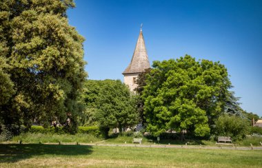 The tower and spire of Holy Trinty Church in Bosham, West Sussex, UK, seen through the tress near the waterfront at Chichester Harbour clipart