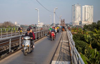 Motosikletli insanlar, Gia Lam 'dan şehir merkezine kadar Hanoi, Vietnam' daki Kızıl Nehir üzerinden Long Bien Köprüsü 'nü geçtiler..