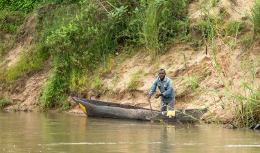Bir adam, Mwaseni 'deki Rufiji Nehri' nde, Tanzanya 'daki Nyerere Ulusal Parkı' nda (Selous Game Reserve) balık tutmaya hazırlanırken, yedek kanosunda duruyor..