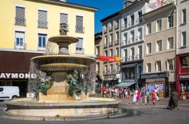 İnsanlar Grenoble, Fransa 'nın merkezindeki Place Grenoble' daki Lavalette Çeşmesi 'nin önünden geçiyor güneşli bir cumartesi öğleden sonrasında..