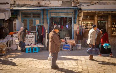 An elderly Tunisian man stops to look at his mobile phone in the souk in the ancient medina of Kairouan in Tunisia. Kairouan is the 4th holiest city in Islam and is a UNESCO World Heritage Site. clipart