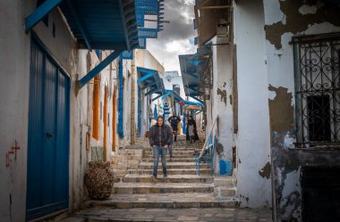 Bir adam Rue el Aghalba 'da merdivenlerden iniyor. Antik Medine' de Susa, Tunus 'ta küçük bir patika. Medine UNESCO 'nun Dünya Mirası Bölgesi.