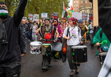 Londra / İngiltere - 21 Ekim 2023: Filistin yanlısı protestocular, İngiltere 'nin orta kesiminde İsrail' in Gazze 'ye düzenlediği saldırılara karşı düzenlenen büyük bir gösteride diğer protestocuların yanında davul çalıyorlar.