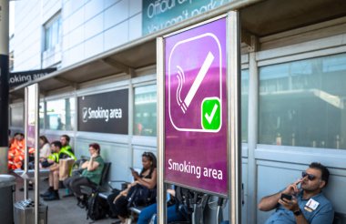 İnsanlar Londra Gatwick Havaalanı, Güney Terminali, Batı Sussex, İngiltere 'de resmi bir açık hava sigara içme alanında sigara içiyorlar..