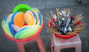 Plastik tabaklar, metal kaşıklar ve çubuklar, Vietnam 'ın Orta İskoçya' sındaki Pleiku 'da kaldırımda kururken plastik elek şeklinde dizilmiştir..