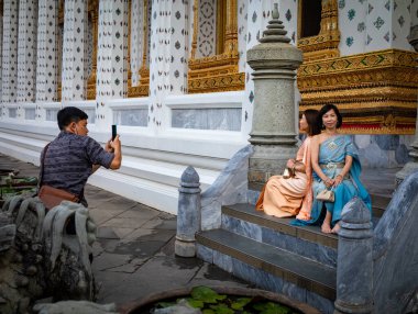 Geleneksel Tayland kostümlü iki Vietnamlı kadın turist, Bangkok, Tayland 'daki Wat Arun' da poz veriyor..
