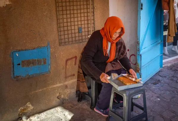 stock image An elderly Tunisian woman sells homemade cake in a small lane within the ancient walled medina of Sousse in Tunisia.