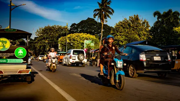 Genç bir kadın Siem Reap Nehri 'nin yanındaki Kamboçya' da Siem Reap 'in merkezinde motosiklet kullanıyor..