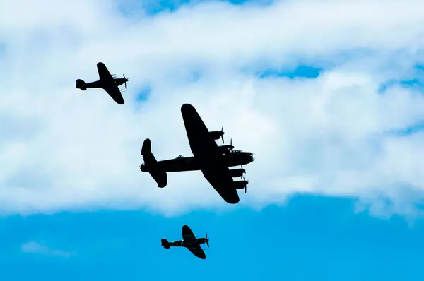 stock image The Battle of Britain Memorial Flight comprising WW2-era Lancaster, Spitfire and Hurricane are seen in silhouette as they fly past the seafront at the annual Eastbourne Airbourne, an international airshow