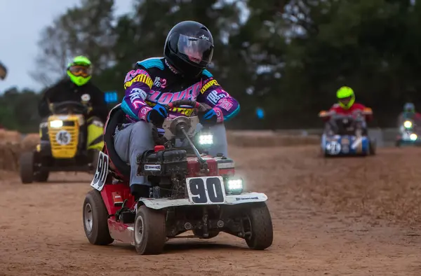 stock image Racing lawn mower drivers bounce around a corner at dawn after driving all night in the BLMRA 500, a Le Mans style 500 mile overnight lawn mower race in a field in West Sussex, UK.