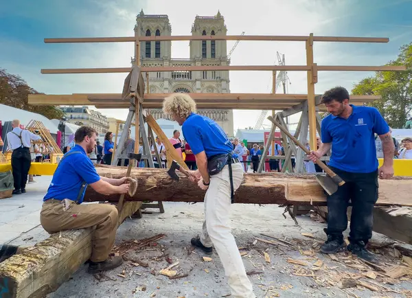 stock image French artisan carpenters and woodworkers demonstrate using traditional axes to prepare oak to be used in the renovation of Notre Dame Cathedral in Paris, France