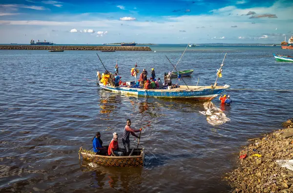 stock image Fishermen in a dhow and a small boat arrive at Darajani Market, or the fish market, in Stone Town, Zanzibar, Tanzania.