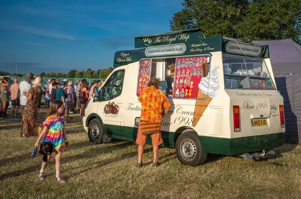 Guildford / UK - 29 Haziran 2024: Genç bir kız Guildford, Surrey, İngiltere 'deki Guilfest müzik festivaline bakarken bir erkek dondurma satın alıyor.