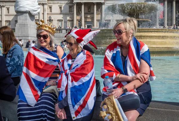 stock image Three women wrapped in Union Flags sit in Trafalgar Square in London during celebrations for the Queen's Platinum Jubilee on 2 June 2022