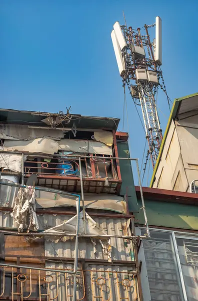 stock image A 5G mobile phone telephone transmission mast fixed to the roof of delapidated houses in central Hanoi, Vietnam.