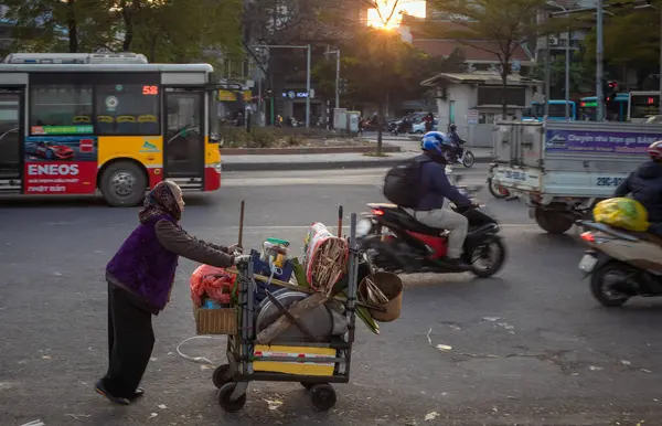 Çok yaşlı bir borsa simsarı mallarını Yen Phu Yolu 'ndaki trafik arasında Hanoi, Vietnam' daki Long Bien Market 'e doğru itiyor..