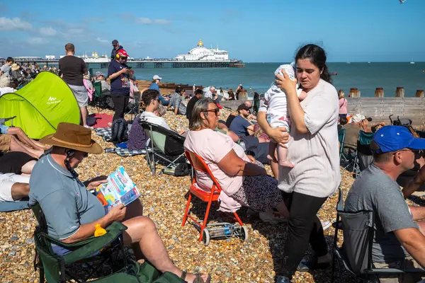 stock image A mother holds her young baby as people crowd the beach next to Eastbourne Pier as they attend the annual Eastbourne Airbourne, an international airshow