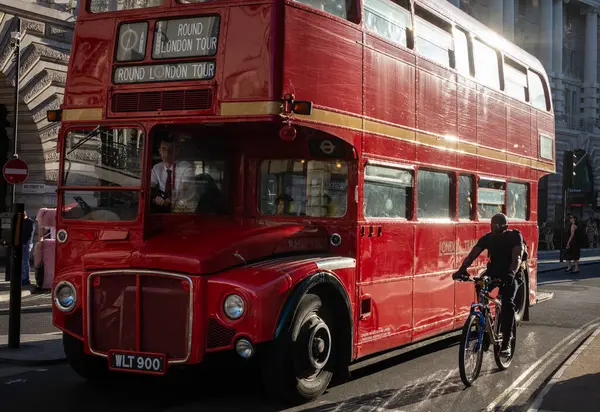 Londra turlarında kullanılan geleneksel kırmızı bir Routemaster Londra otobüsü bir bisikletçinin yanından geçer. Londra, İngiltere, İngiltere